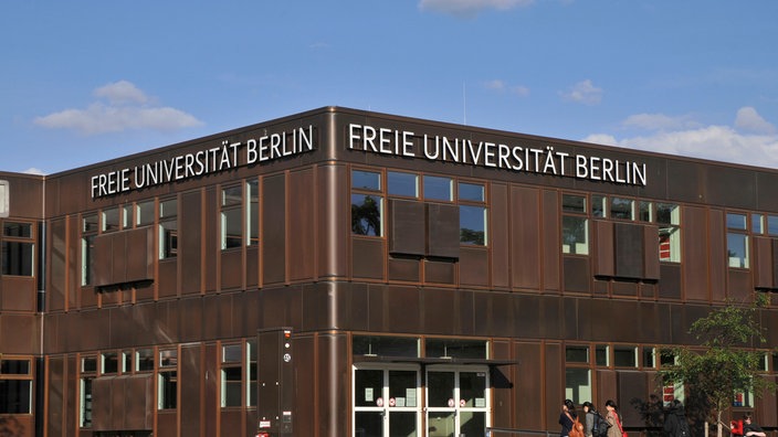 freie Universität Berlin, in rostbraunem Farbton, Hauptgebäude, davor gehen Menschen