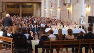  Blick in die volle Moritzkirche - Diakon Feuersträter segnet die Jugendlichen