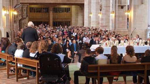  Blick in die volle Moritzkirche - Diakon Feuersträter segnet die Jugendlichen