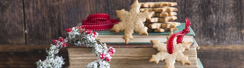 Weihnachtsplätzchen und Dekoration auf einem Stapel Bücher.