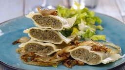 Maultaschen, aufgeschnitten und platziert auf einem blauen Teller.