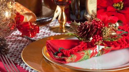 Ein gedeckter Tisch mit roter und goldener Weihnachtsdeko.
