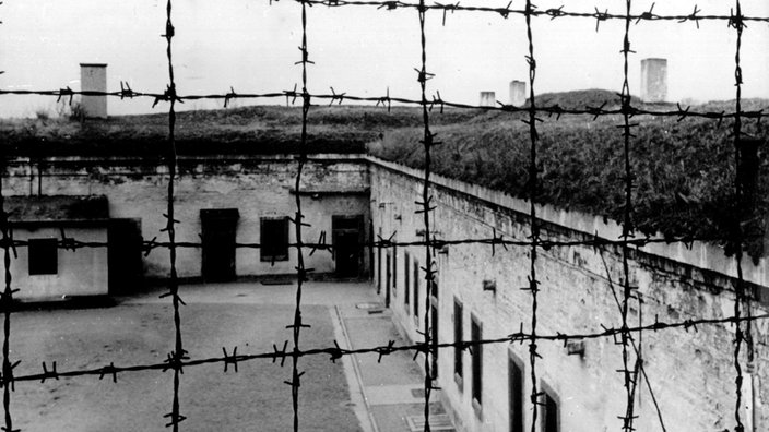 Blick durch Stacheldraht auf die Gebäude des 1941 von der SS errichteten Konzentrationslagers im tschechischen Theresienstadt. 