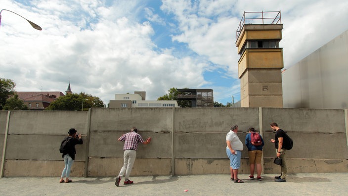 Gedenkstätte Bernauer Straße an der ehemaligen Mauer in Berlin, Deutschland: Besucher betrachten den Wachturm und Todesstreifen.