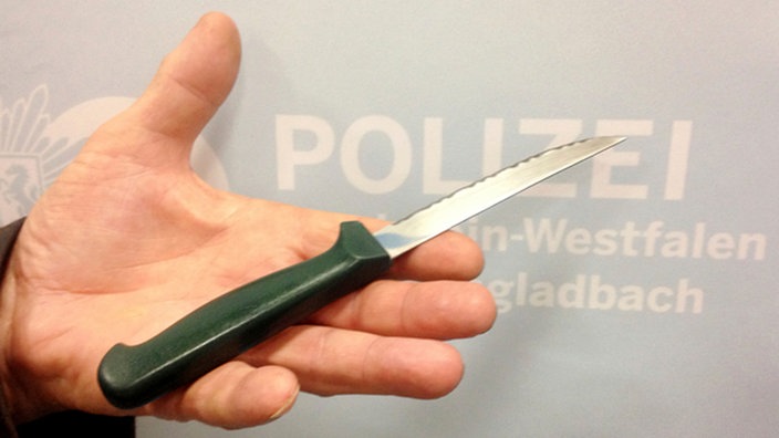 Ein Polizist zeigt ein Messer, mit dem eine Straftat verübt wurde.  