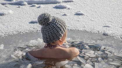 Eine junge Frau in einem Wasserloch beim Eisbaden