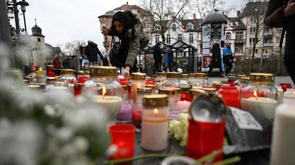 Auf einem Platz in Aschaffenburg stehen am 23. Januar 2025 Grabkerzen und Blumen