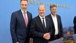 Christian Lindner, Olaf Scholz und Robert Habeck lächeln auf der Pressekonferenz in die Kameras