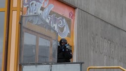 Bewaffneter Polizist in Schutzausrüstung bei einer Übung an einem Schulgebäude