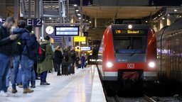 Menschen stehen am Bahnsteig, während eine Regionalbahn einfährt. Symbolbild: Pendler:innen