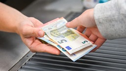 Kunde im Supermarkt gibt Geld an Kassierer