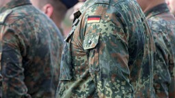 Symbolbild: Soldat:in mit Feldbluse in Flecktarn mit dem Hoheitszeichen der Bundesrepublik Deutschland.