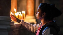 Eine Frau zündet eine Kerze in einer Kirche in Jerusalem an. Symbolbild, Archivbild: 14.12.2023