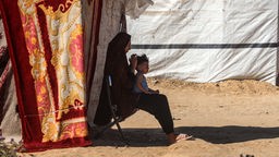 Eine Palästinenserin sitzt mit einem Kind vor ihrem Zelt während einer Hitzewelle in Deir al-Balah im zentralen Gazastreifen am 11. Juni 2024.