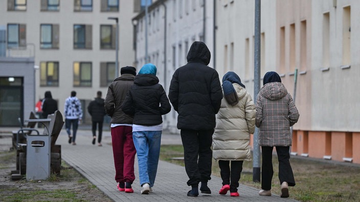 Menschen gehen über das Gelände der Zentralen Erstaufnahmeeinrichtung für Asylbewerber (ZABH) des Landes Brandenburg in Eisenhüttenstadt (2023).