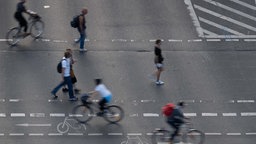 Fußgänger:innen und Radfahrer:innen überqueren eine Straße.