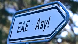 Auf einem Wegweiser steht "EAE" und "Asyl"