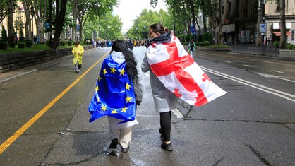 Zwei Menschen mit georgischer National- und EU-Flagge während eines Protestes der Opposition gegen das "russische Gesetz" in Tbilissi (13.05.2024)