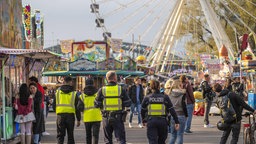 Mitarbeiter eines Sicherheitsdienst und Polizeistreife gehen über die Deutzer Kirmes