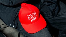 Eine rote Baseballkappe mit dem Schriftzug "TAX THE RICH - Die Linke"