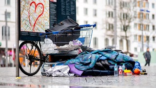 Hab und Gut eines obdachlosen Menschen liegt auf dem Boden in einer Fußgängerzone