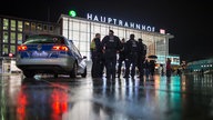 Polizisten stehen neben einem Einsatzwagen vor dem Kölner Hauptbahnhof