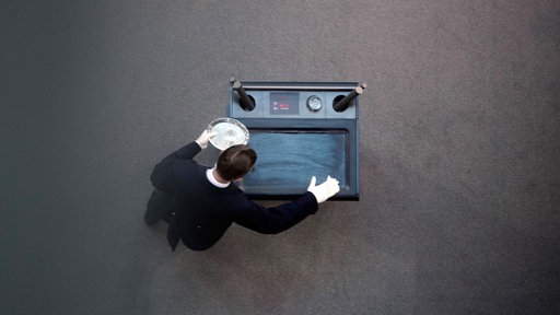 Symbolbild: Ein Saaldiener bereitet während der Corona-Pandemie im Bundestag den Rednerpult vor.