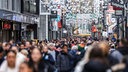 Menschen gehen in Köln durch die Einkaufsmeile Hohe Straße in der Fußgängerzone. 