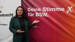 Sevim Dagdelen steht an einem Wahlplakat des Bündnis Sahra Wagenknecht