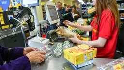 Eine Kassiererin scannt Ware in einem Supermarkt ein.