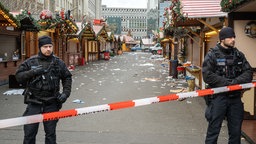 Polizisten stehen vor dem abgesperrten Weihnachtsmarkt in Magdeburg. 