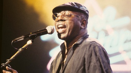 Curtis Mayfield singend auf der Bühne. 