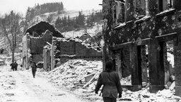 Soldaten auf den Straßen des verschneiten und zerbombten Houffalize, Belgien, im Januar 1945