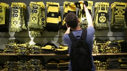 Ein Mann schaut sich im Fanartikel-Shop von Borussia Dortmund am Signal-Iduna-Park in Dortmund einen Schal an.