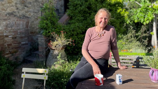 Cornelia Funke sitzt in ihrem grünen Garten ihres Hauses in Italien.