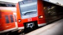 Eine rote Regionalbahn der Deutschen Bahn fährt in einen Bahnhof ein, vom Bahnsteig aus fotografiert.