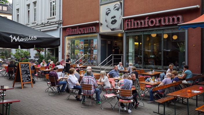 Besucher sitzen vor dem Filmforum Duisburg