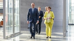 Friedrich Merz, Saskia Esken, Lars Klingbeil und Markus Söder gemeinsam einen Gang entlang. 