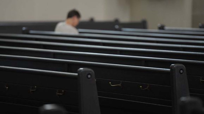 Ein Besucher sitzt allein in einer Kirche.