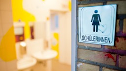 Ein Schild "Schülerinnen" hängt an einer Schultoilette eines Gymnasiums