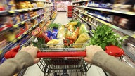 Hände an einem vollen Einkaufswagen in einem Supermarkt