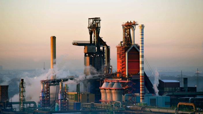 Aus dem industriell gepägten Thyssenkrupwerk im Winter steigt Rauch auf.