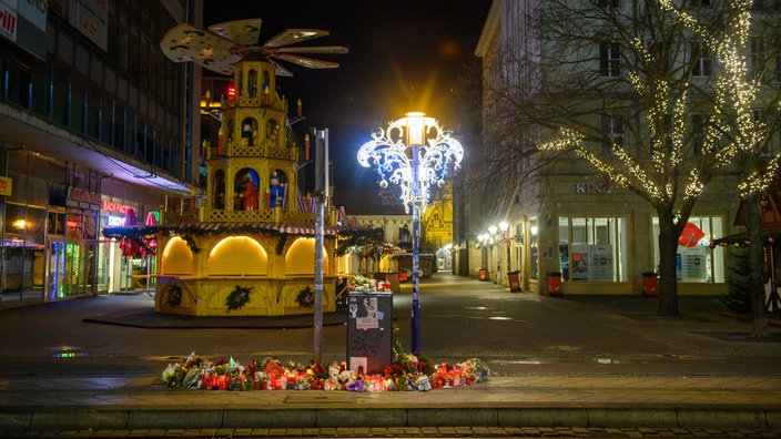 An der Zufahrt zum Weihnachtsmarkt stehen Kerzen und Blumen.