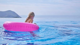 Zwei Kinder plantschen im Wasser von einem See im Sommer.