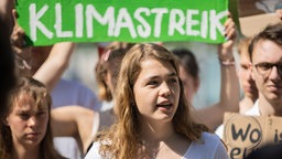 Annike Rittmann von Fridays for Future bei einem Protest mit vielen Menschen, im Hintergrundn ein Banner mit der Schrift 'Klimastreik'