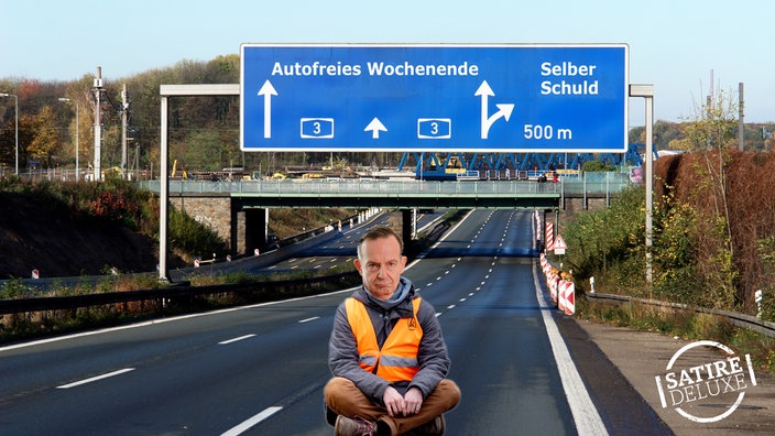 Volker Wissing sitzt in Blockade-Haltung auf einer leeren Autobahn