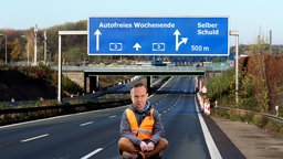 Volker Wissing sitzt in Blockade-Haltung auf einer leeren Autobahn