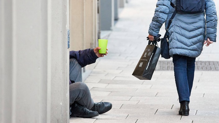 Ein Mann sitzt bettelnd in der Fußgängerzone 