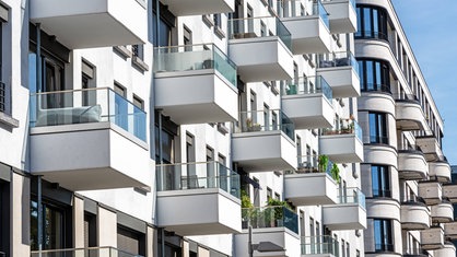 Die Fassade eines weißen modernen Wohnhauses mit vielen kleinen Balkonen.