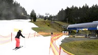 Eine Skifahrerin fährt auf einem Kunstschneestreifen zu einer Liftstation, Archivbild: 26.12.2022